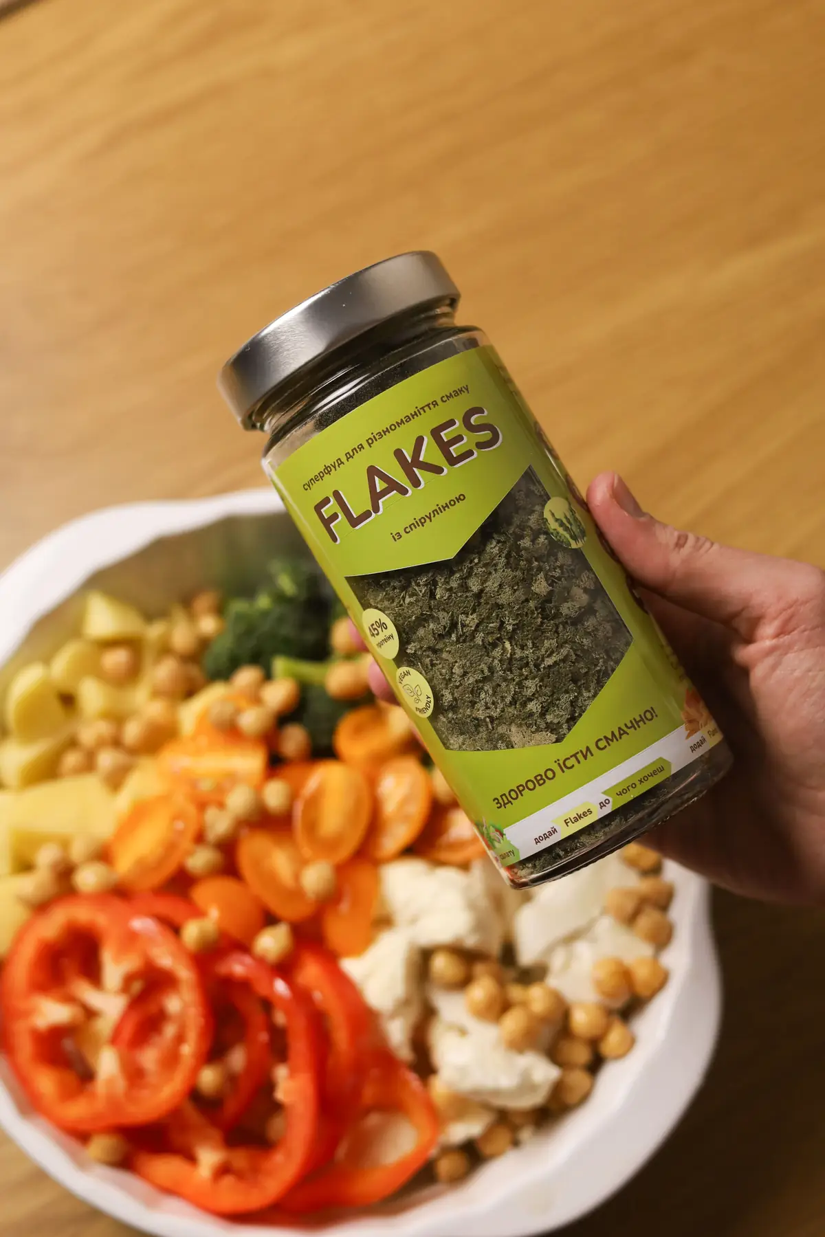 Flakes зі спіруліною над мискою з овочами перед запіканням